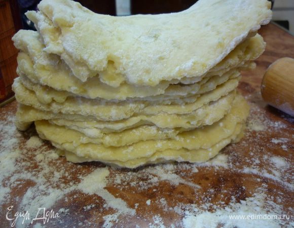 От теста отламываем кусочки размером с грецкий орех, на хорошо посыпанном мукой столе раскатываем лепешки толщиной полсантиметра и складываем их друг на друга. У меня получилось 19 штук.