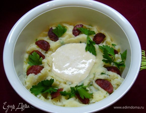 Выложить пюре в салатник, в центре сделать углубление, влить в него оставшуюся заправку. Разложить кусочки колбасы, украсить петрушкой.