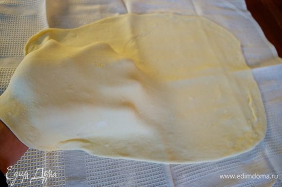 Переложить тесто на чистое полотенце и растянуть немного руками.