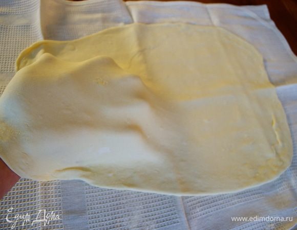 Переложить тесто на чистое полотенце и растянуть немного руками. 