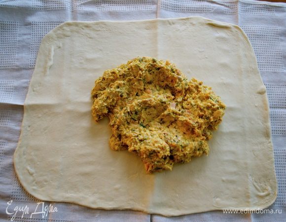 Выложить начинку на тесто, оставив с одной длинной стороны 5 см, и разровнять в ровный слой.