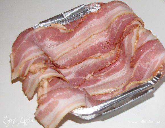 Форму для запекания выстлать полосками бекона так, чтобы края свисали.