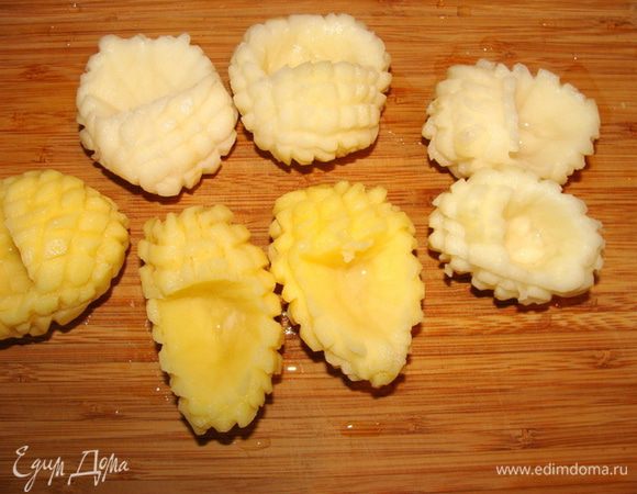 Картофель очистить, положить в воду чтобы не потемнел. Доставать по одной картофелине, формировать из нее лапоточек и опускать опять в воду. Дело не секундное. Можно делать это специальным ножом, мне пришлось мастерить бороздки кончиком ножа для нарезки сыра. На целой картофелине провести бороздки в двух поперечных направлениях, потом вырезать серединку, придав форму лаптя.