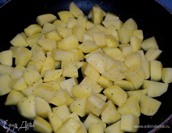 В большую сковороду налить оливковое масло и положить обжариваться картофель. Посолить и поперчить по вкусу. Обжаривать 5 минут на сильном огне. Затем накрыть крышкой, уменьшить огонь и продолжать готовить еще 20 минут, время от времени осторожно перемешивая (или встряхивая) картофель.