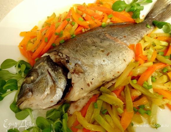 Запеченную рыбку достать из фольги, выложить вместе с овощами на тарелку. Украсить зеленью.