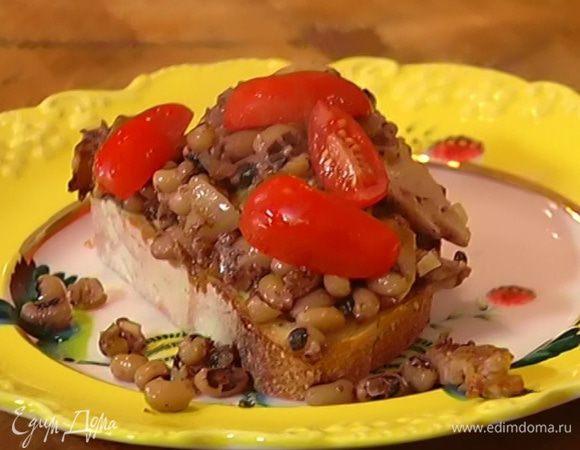 На хлеб выложить фасоль с грибами, сверху украсить помидорами черри.