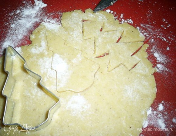  Раскатываем тесто тонко (не больше 5 мм).  Это лучше делать, припудрив тесто и рабочую поверхность мукой. Вырезаем выемкой елочки. Если у вас нет формочки елочки, можете просто вырезать елочки ножом. Так вы получите эксклюзивные и неповторимые елочки ручной работы.