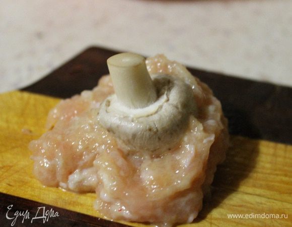 Далее берем небольшую горсть фарша, расплющиваем его руками и кладем сверху грибок шляпкой вниз. Потом собираем весь фарш с боков, облепляя грибок. Лучше всего заворачивать грибок руками, а не на доске.)