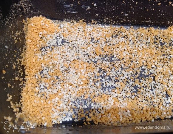 Форму для выпечки смазать маслом и присылать сухарями (1/2), добавить кунжут (1/2).