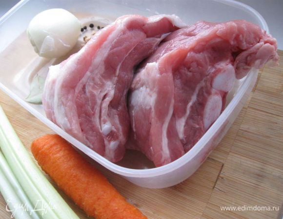 Приготовить все необходимое. Чеснок не чистить, разрезать на 2 части поперек. Морковь и лук почистить. Луковую шелуху помыть. Свинину положить в небольшое количество кипящей воды (она должна быть прикрыта водой на 2 пальца сверху, не больше), добавив морковь, чеснок, лавровый лист, луковую шелуху (для цвета), корень петрушки, лук, стебли сельдерея, перец горошком.