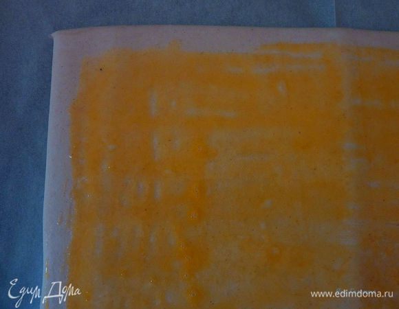 Желток перемешать с водой. Помазать тесто желтком оставляя 2 см по краю с бортиков.
