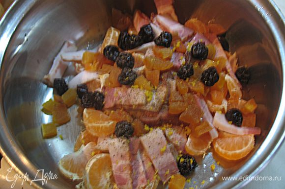 Готовим начинку для курицы. В миске смешиваем 4 мандарина разделенных на дольки, цукаты, порезанный на полоски бекон. Добавляем пару ложек оливкового масла, молотого черного перца, цедру лимона и перемешиваем.