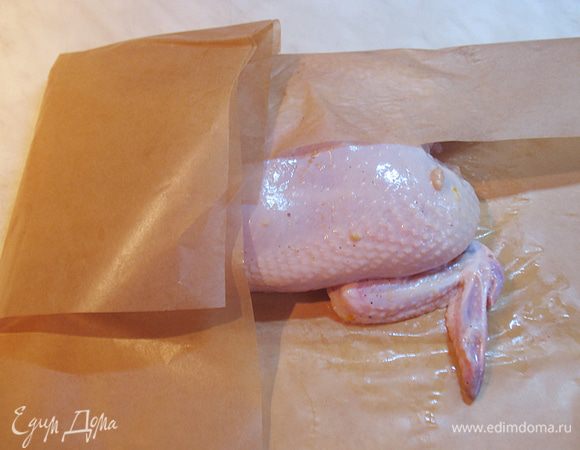 Сначала заворачиваем нашу курицу в пергамент.  Подготавливаем пергамент - отрываем два листа пергамента и складываем один с заходом на другой.  Выкладываем на пергамент курицу и плотно заворачиваем в него курицу. 