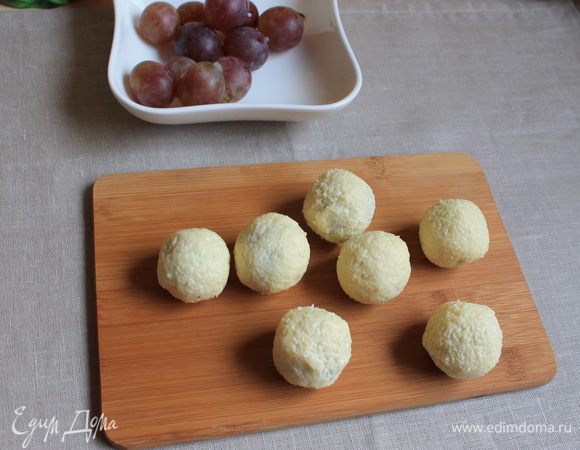 Виноград помоем, и удалим косточки при помощи зубочистки. Далее сделаем шубку. Берем виноград и накладываем на него сырную массу с двух сторон, чайной ложкой. Затем катаем руками как шар. Очень хорошо прилипает.
