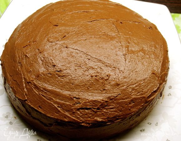 Затем накрыть вторым коржом, снова пропитать сиропом и нанести половину шоколадной глазури. Сверху положить третий корж, пропитать сиропом и покрыть оставшейся половиной глазури, не забыв смазать хорошо бока торта.