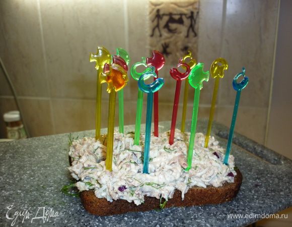 Берем ломтик какого-нибудь интересного хлеба. Отлично для этого подходит Бородинский, Зерновой. Намазываем весь ломтик густо, щедро. А теперь берем симпатичные шпажки. Зубочистки тоже подойдут. Мысленно поделим кусок на канапешки. И в задуманные центры канапе вонзаем шпажки. И пусть в этот момент будем прекрасными рыбачками с трезубцем ....или двузубой шпажкой....