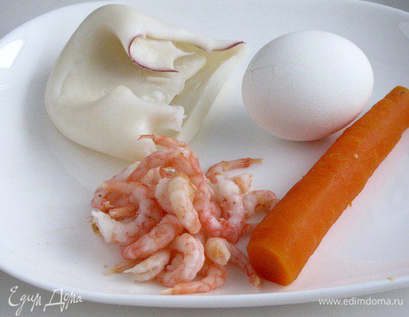 Отварить кальмары и креветки в подсоленной воде. Отварить яйца и морковь. Кальмары нарезать очень тонкой соломкой.