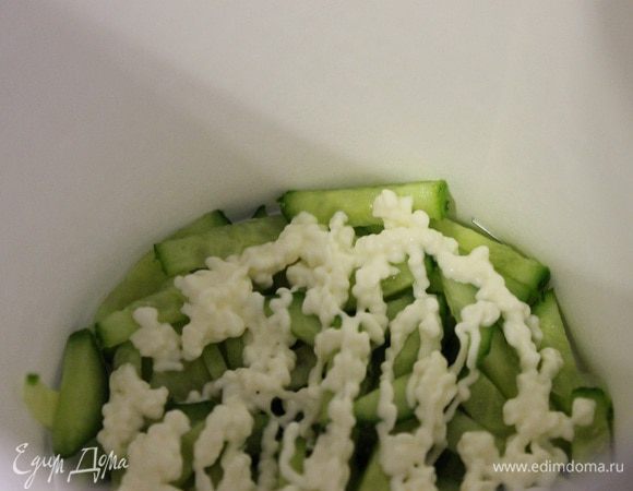 Сервировочное кольцо ставим на тарелку, выкладываем в него огурец порезанный соломкой, хорошо его утрамбовываем, смазываем сеточкой майонеза.