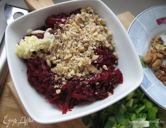 В свеклу добавить измельченный чеснок и растертые орехи. Часть растертых орехов оставить на украшение.

