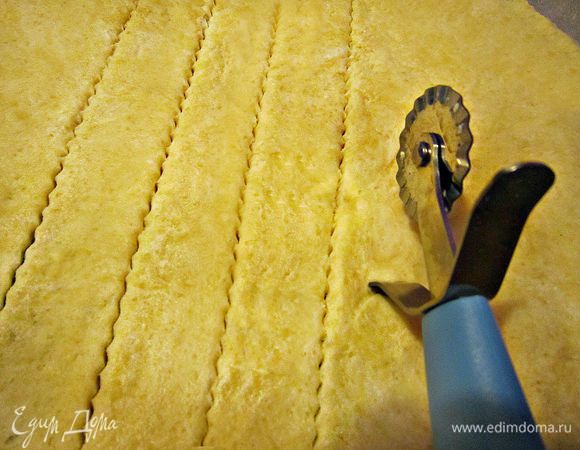 Противень застелить пекарской бумагой. Раскатать тесто и вырезать палочки с помощью ножа-ролика...