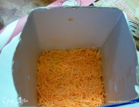 Сервировочную "коробочку" ставим на тарелку. Натираем меленько морковь, кладем на дно и тщательно утрамбовываем.