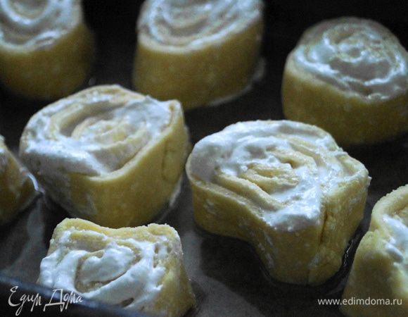 Скатать тесто с начинкой в рулет и нарезать на кусочки толщиной 2-3 см. Делать это нужно быстро и острым ножом, так как начинка может вытечь. Выложить получившиеся кусочки на противень и поставить в разогретую до 200 градусов духовку. Выпекать до образования нежно-золотистого цвета.