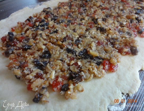 Охлажденное тесто раскатать на подпыленной поверхности (лучше сразу на бумаге для выпечки) в прямоугольник размером 25*35 см. Начинку распределить по тесту, оставляя 2 см. свободного края.