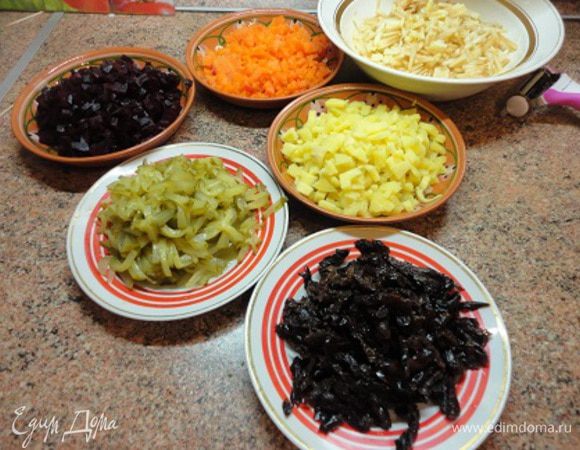 Все овощи можно натереть на крупной терке, но я предпочитаю нарезать ножом: картофель, морковь и свеклу – кубиками. Яблоки очистить и нарезать соломкой. Огурцы тоже нарезать соломкой и дать стечь рассолу. Чернослив нарезать соломкой.