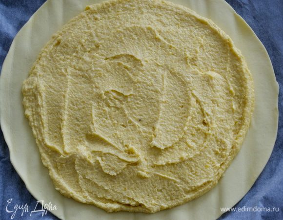 Достаем из холодильника оба диска из теста. Первый диск кладем вместе с бумагой на противень. Наносим и равномерно распределяем по поверхности теста крем-франжипан. Не доходя до края коржа 2-3 см.