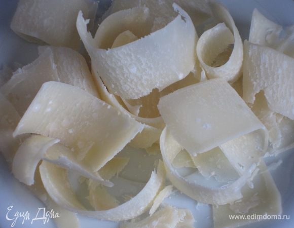  С помощью овощечистки нарезать пармезан хлопьями.