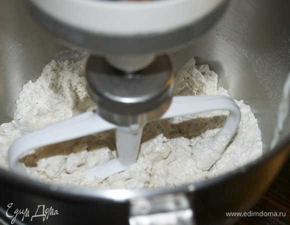 Включить тестомешалку на медленную скорость и начать перемешивать все сухие ингредиенты, постепенно вливая теплое молоко. 
