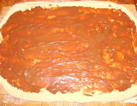 Шоколадные конфеты типа "Маски" и шоколад растопить на водяной бане, смешать со сметаной и сахарной пудрой. Остудить. 1/2 частью смазать тесто, оставляя края по 1.5-2 см.