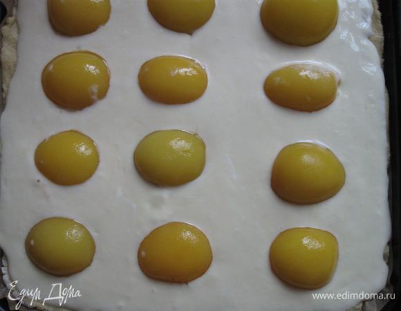 Тесто вынуть из холодильника, раскатать. Противень застелить пекарской бумагой. Выложить на бумагу тесто, разровнять его, затем положить начинку. На нее – персики. 