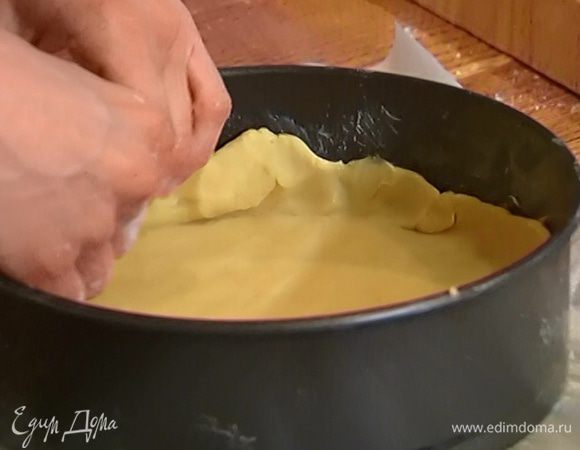Рабочую поверхность посыпать мукой, раскатать половину теста в тонкий пласт и выложить его на дно формы, сформировав небольшие бортики.