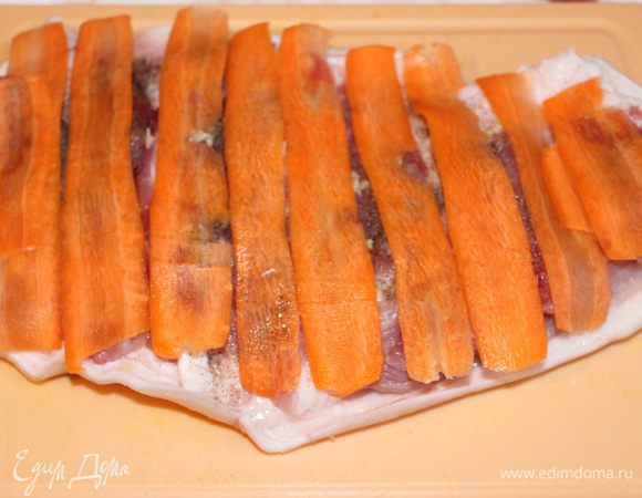 Нарезаем тонко сырую морковь, при помощи овощечистки. Выкладываем полоски на рульку.