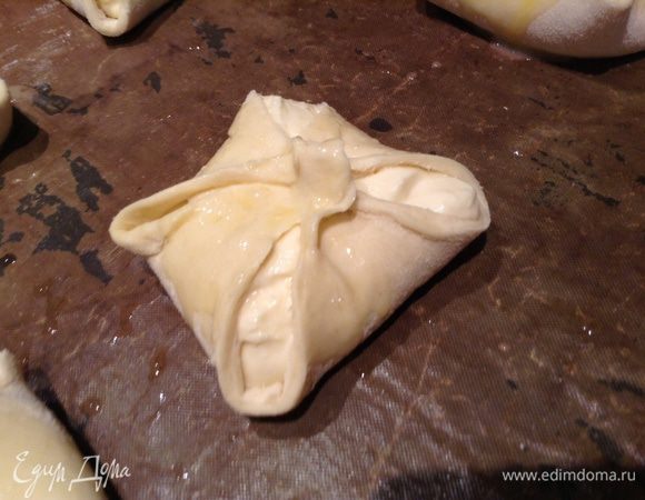 В каждый квадрат положить ст ложку творожной массы. сложить концы квадратов к центру и слепить. сверху смазать взбитым яйцом.