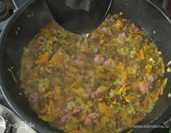 Затем добавить чуть меньше литра бульона (750 мл), накрыть сковороду крышкой, уменьшить огонь и варить все 1 час 15 минут. Если Вы используете консервированную чечевицу, то добавить меньшее количество бульона и потушить все 15-20 минут.