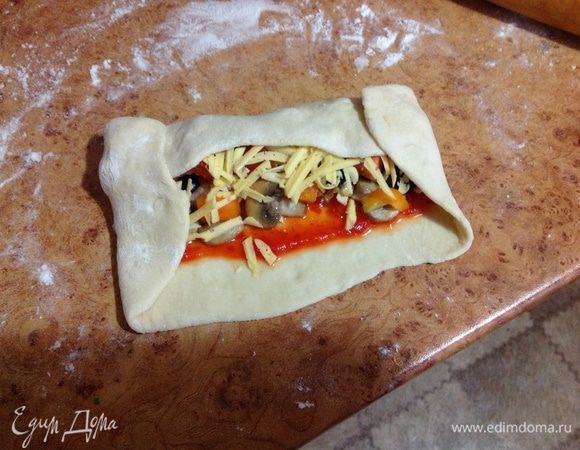 Завернуть короткие края теста, затем по длине свернуть рулетом.
