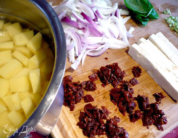 Почистим картофель. Нарежем сельдерей мелко, а картофель - крупным кубиком. Фету разрежем вдоль на шесть частей. Тимьян отделим от веточек. 6 листочков базилика промоем, обсушим бумажным полотенцем. Помидоры (6 шт.) промокнем бумажным полотенцем и нарежем мелким кубиком. Лук (у меня мелкий, поэтому я использовала 4 штуки) нарежем на половинки, каждую половинку — полосками. Обжарим лук на сливочном масле (20 г) до прозрачности.  