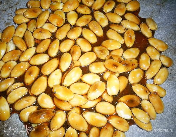  Всыпаем обжаренный миндаль в карамель, все перемешиваем и выливаем содержимое на пергамент. Равномерно распределяем массу и даем остыть.