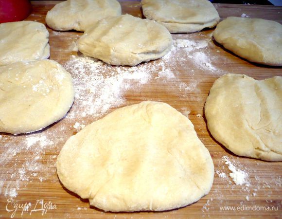 На хорошо присыпанной мукой поверхности скатываем тесто в багет и делим его на 9 равных частей, каждую часть немного разминаем руками в лепешку.