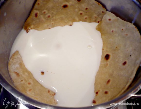 Каждую из лепешек раскатываем на щедро присыпанной мукой поверхности в тонкую лепешку диаметром примерно 20 см. Обжариваем лепешку на раскаленной сковороде, слегка смазанной оливковым маслом (мне помогала силиконовая кисточка) с каждой стороны до тех пор, пока на лепешке не начнут появляться коричневатые пузырьки. После обжаривания нескольких лепешек стоит вытирать сковороду сухим бумажным полотенцем, чтобы на ней не оставалось пригоревшей муки. Как только лепешка обжарилась сразу погружаем ее в молоко комнатной температуры.