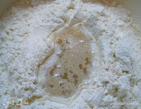 Теперь займемся тестом. Муку просеять в миску, сделать углубление.
В центр углубления добавить дрожжи (4 г – это 1 ч. л. с небольшой горкой).
Влить 50 мл теплой воды. Накрыть и дать постоять 5 мин.
