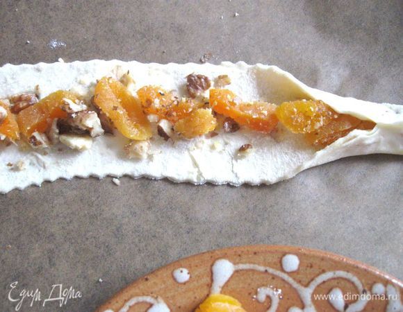 На противне, застеленном пекарской бумагой, разложить на каждой полоске теста поочередно начинки из айвы, чернослива, изюма, кураги.  Защипнуть края теста.