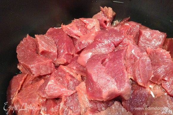 В емкость для мультиварки налить масло, положить мясо и включить режим "выпечка". 10 мин обжарить мясо.