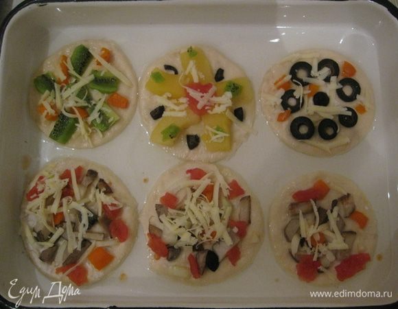Лук, тыкву, киви и оливки порезать. 
На мини пиццы выкладываем грибы и лук. На другие пиццы тыкву, оливки и киви.
С консервированных помидоров снимаем кожицу и распределяем ее все пиццы, кроме фруктовой.
Сверху посыпать тертым сыром. 
