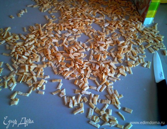 Настоявшееся тесто раскатываем в тонкий пласт (чем тоньше, тем лучше), нарезаем на полоски шириной 1,5 см и следом нарезаем на полоски шириной 0,5 см.