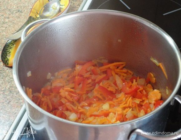 В большой кастрюле разогреть масло. Добавить  морковь, чеснок, лук и перец, обжарить до золотистого цвета. Добавить тмин и порошок красного перца, ½ ч. ложки соли. Готовить 1 минуту.