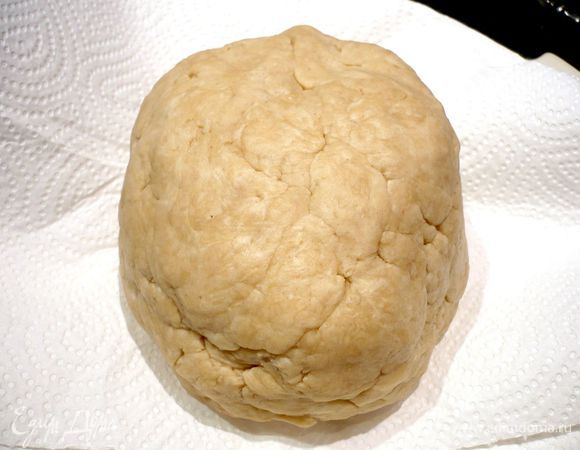 По прошествии почти двух часов приготовим тесто. Для этого муку смешаем с солью в чаше комбайна, добавим размягченное масло и на минимальной скорости вымесим тесто до состояния крошки. Добавим творог, перемешаем и соберем тесто в шар. Слегка прижмем его и, завернув в пленку, уберем в холод на полчаса.