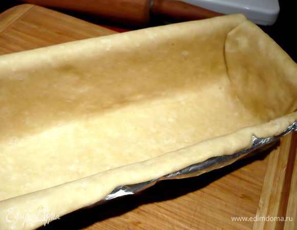 БОльшую часть теста также раскатаем в прямоугольный пласт толщиной 4 мм. Выложим на каждую часть подходящий трафарет (той стороной, на которой мы не чертили карандашом, иначе на тесте останутся отпечатки) и вырежем необходимую для нас форму из теста. Выстелим большей частью теста нашу форму. Другую часть отложим в сторону.